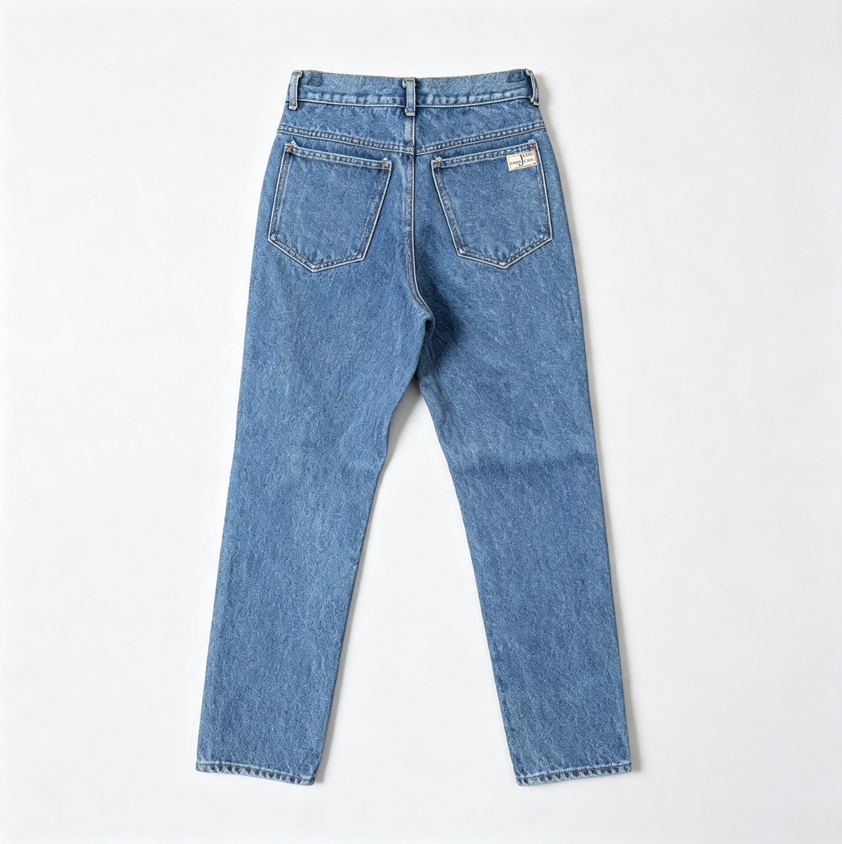 Back view of light blue denim jeans laid flat on a light gray background, showing the waistband, belt loops, back pockets, and hem.