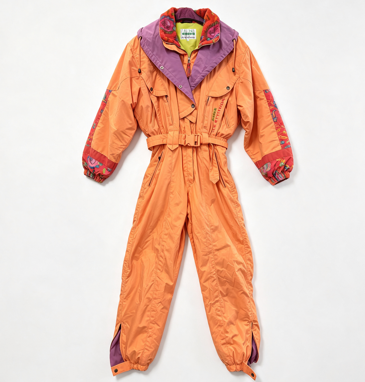 An orange winter jumpsuit laid flat on a white background, featuring a purple hood, a waist belt, and multicolor patterned cuffs and hood trim.