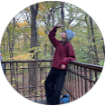 Person standing on a wooden deck with trees in the background