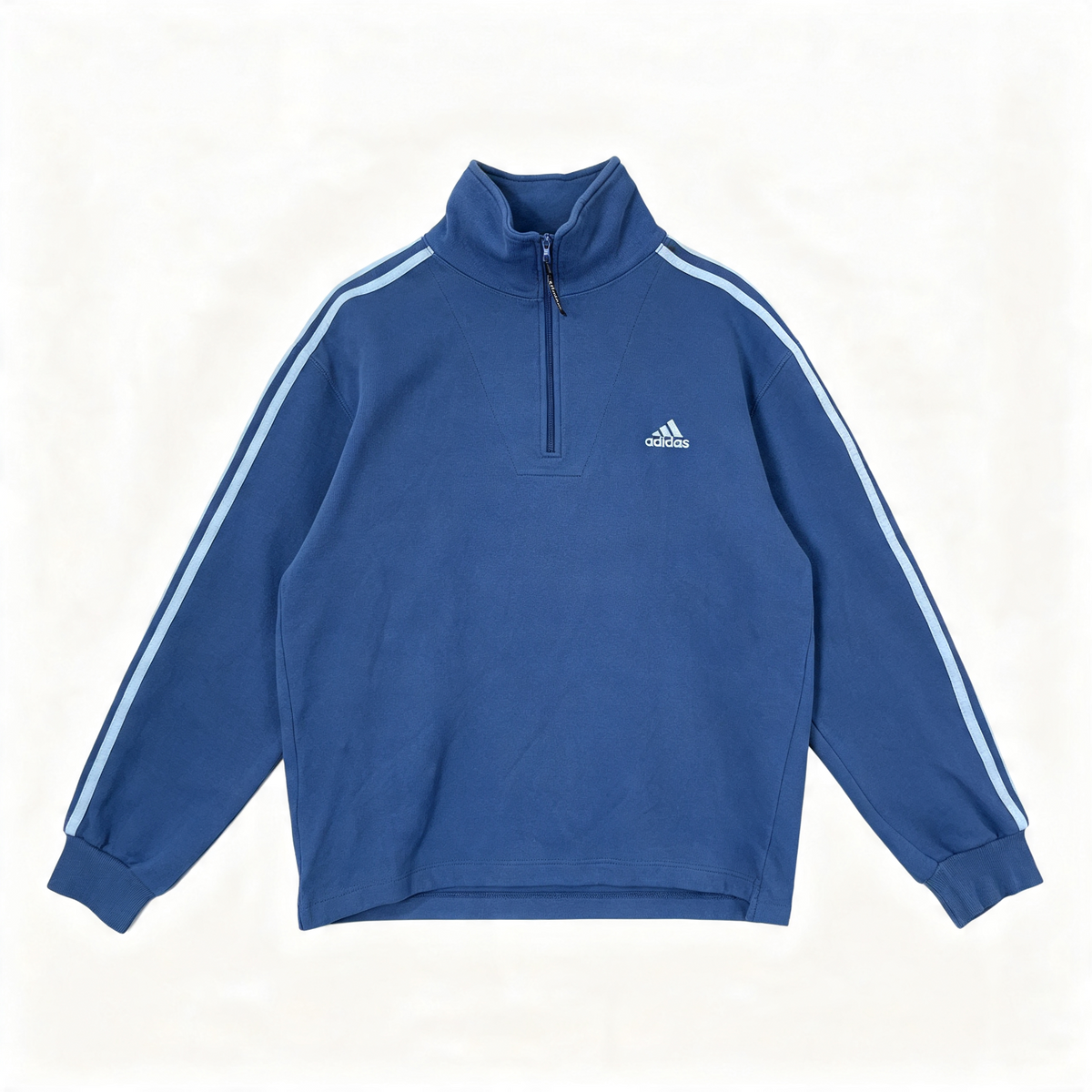 A blue Adidas quarter-zip sweatshirt with white three-stripes on the sleeves and a white logo on the chest, laid flat against a white background.