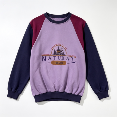 A long-sleeve raglan sweatshirt with a lavender-purple body, dark navy sleeves and collar, and burgundy shoulder panels. The front features a graphic print with the words 'NATURAL FEELING' and a small illustration.