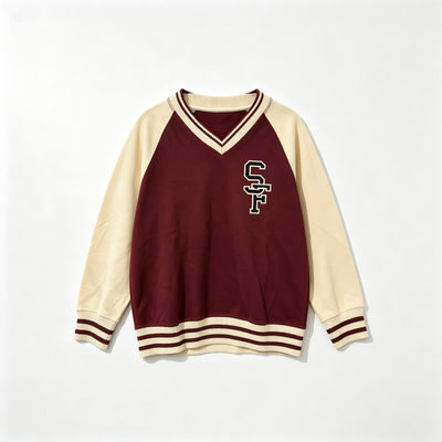 A varsity-style long-sleeve sweater with a maroon body and cream sleeves, featuring a cream and maroon V-neck collar, striped ribbed cuffs and hem, and a cream and maroon 'SF' monogram on the chest.