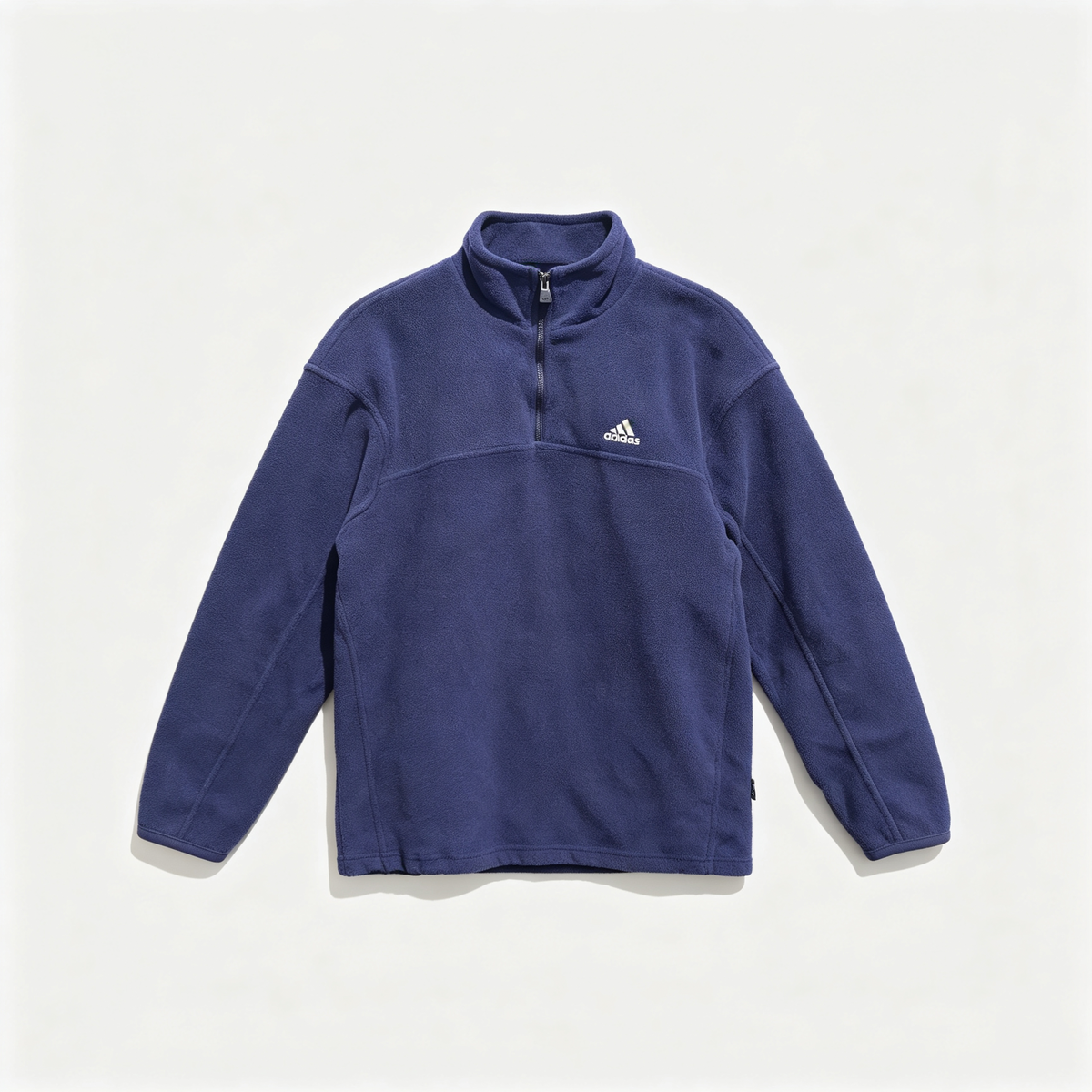A navy blue Adidas quarter-zip fleece pullover with a small white logo on the left chest, displayed flat against a light off-white background.