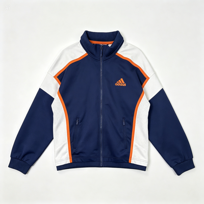 An Adidas track jacket in navy blue, white, and orange, laid flat against a light off-white background. The jacket features a navy blue stand collar, navy sleeves, white side panels, and orange piping accents along the shoulders and sides, with the orange Adidas logo on the left chest.