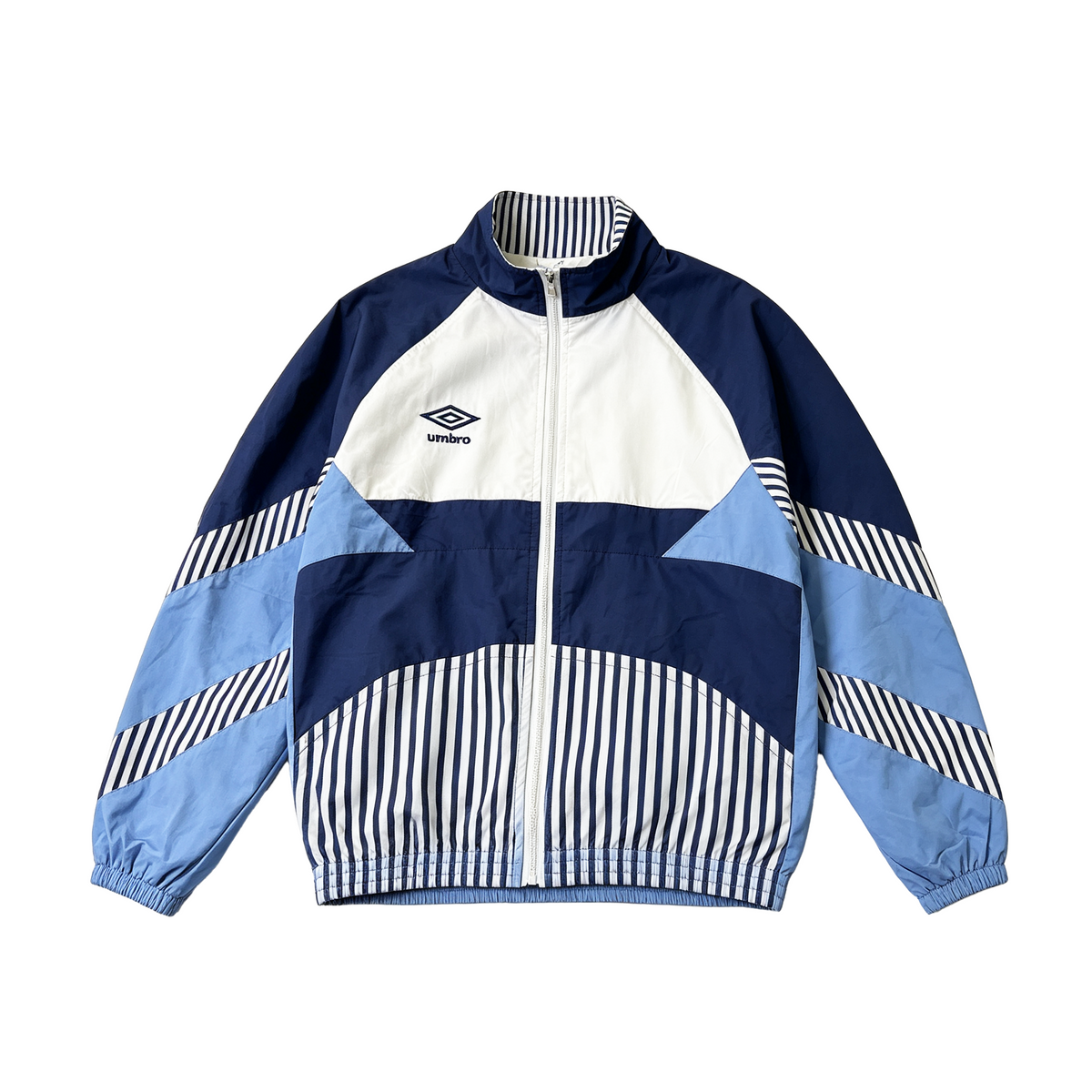 A vintage-style colorblock windbreaker jacket by Umbro, featuring navy blue, light blue, and white panels with striped details, shown flat on a white background.