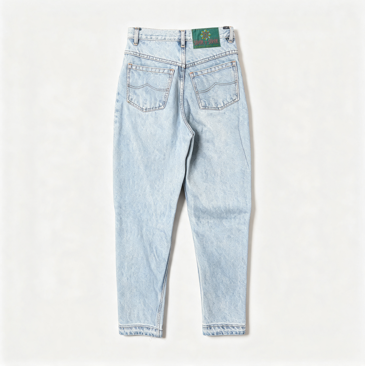 Light wash blue denim jeans shown from the back, featuring a straight-to-slim leg, cuffed hems, and a green embroidered patch on the back waistband.