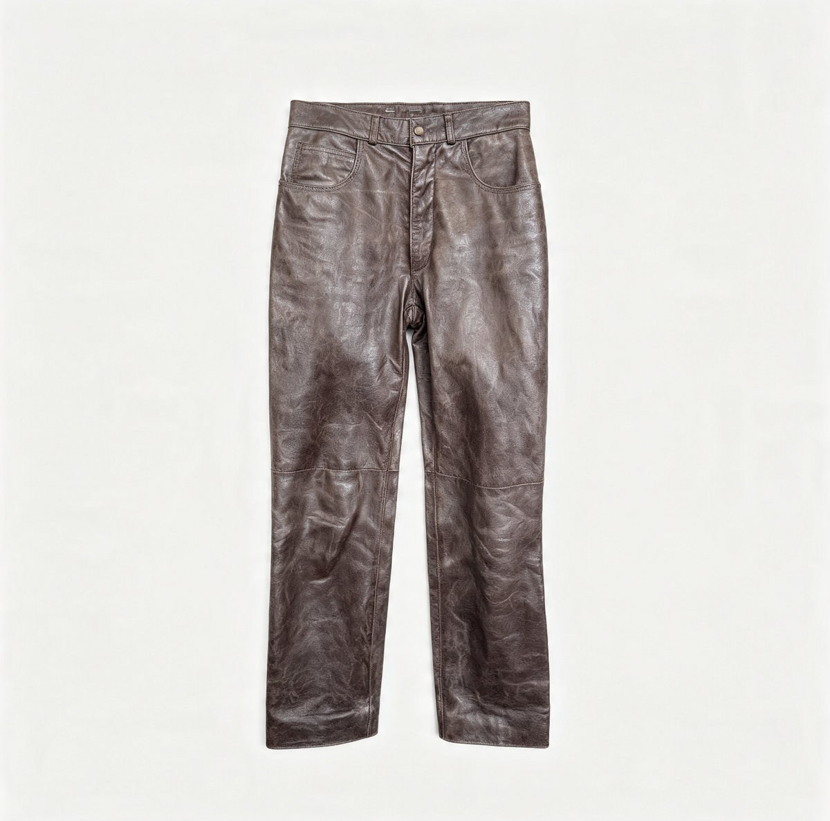 A pair of brown leather pants with a distressed, crinkled texture, laid flat against a solid off-white background.