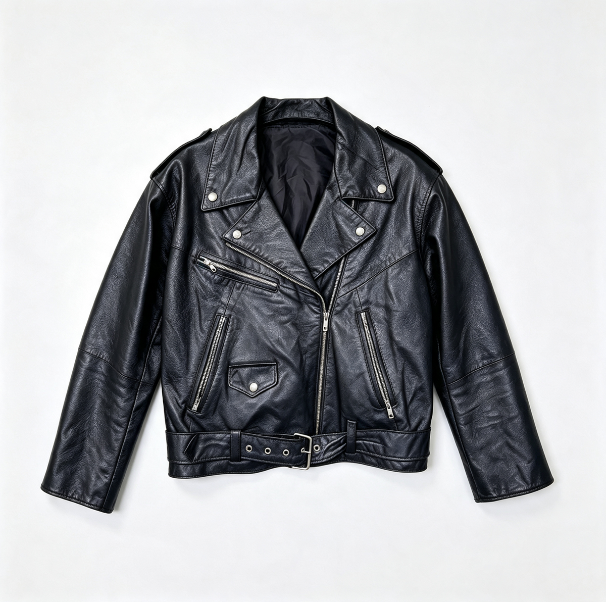 A black leather motorcycle jacket with silver hardware, laid flat against a light gray background.