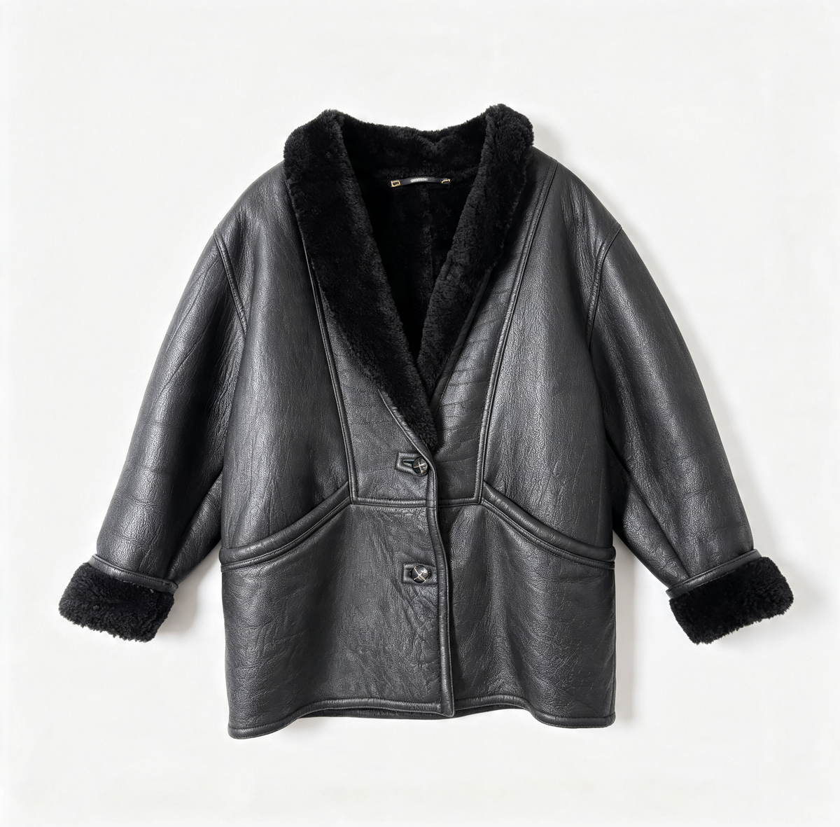 A black leather shearling jacket with a plush black fur collar, button closure, and matching faux-fur trimmed cuffs, shown flat against a light off-white background.