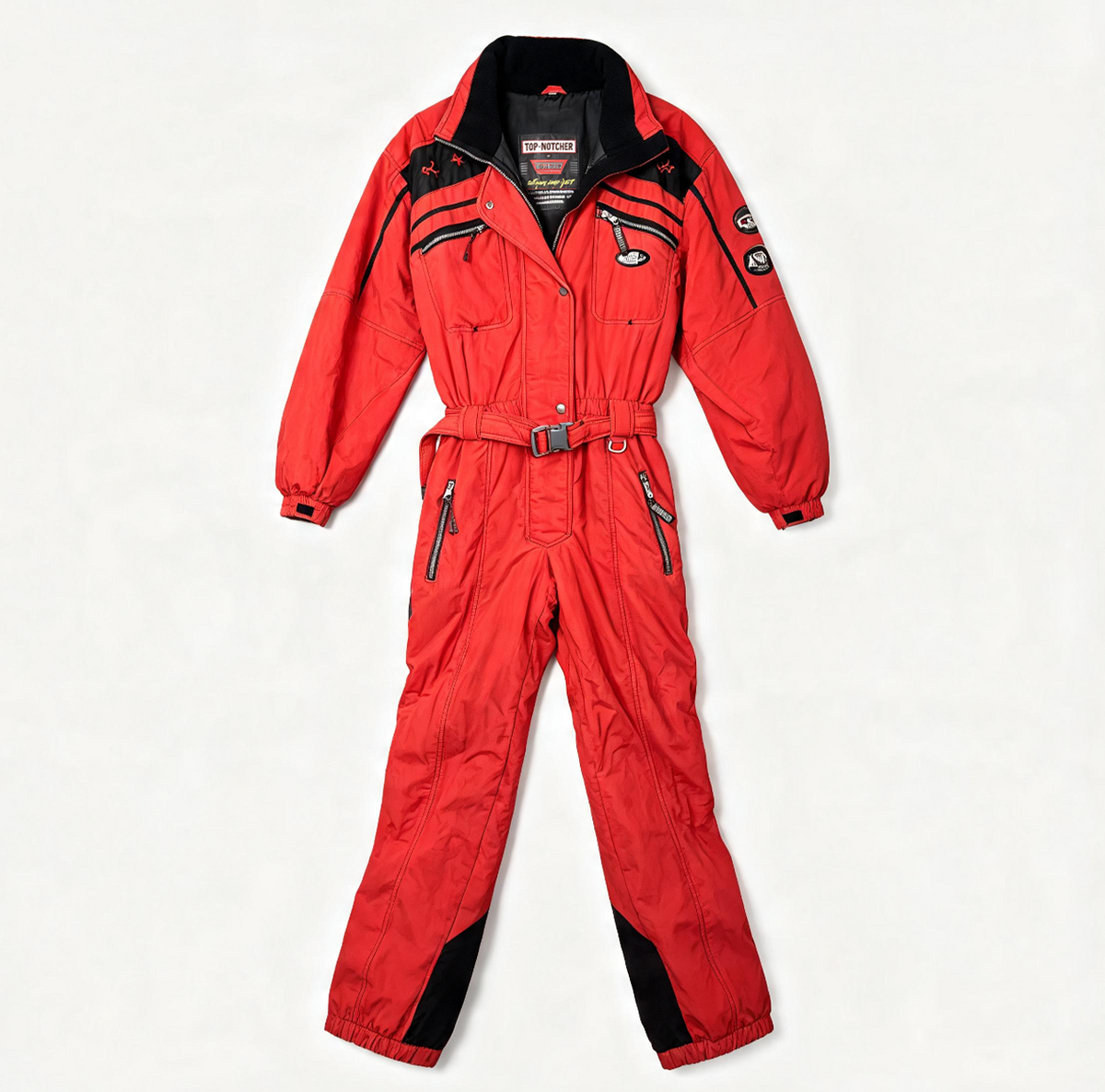 A red one-piece winter jumpsuit with black accents, including a black collar, black shoulder panels, and black knee patches, displayed flat against a light off-white background.