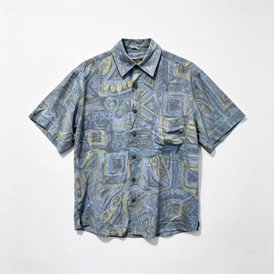 A short-sleeve button-up shirt with an abstract geometric pattern in slate blue, gray, and yellow, laid flat against a white background.