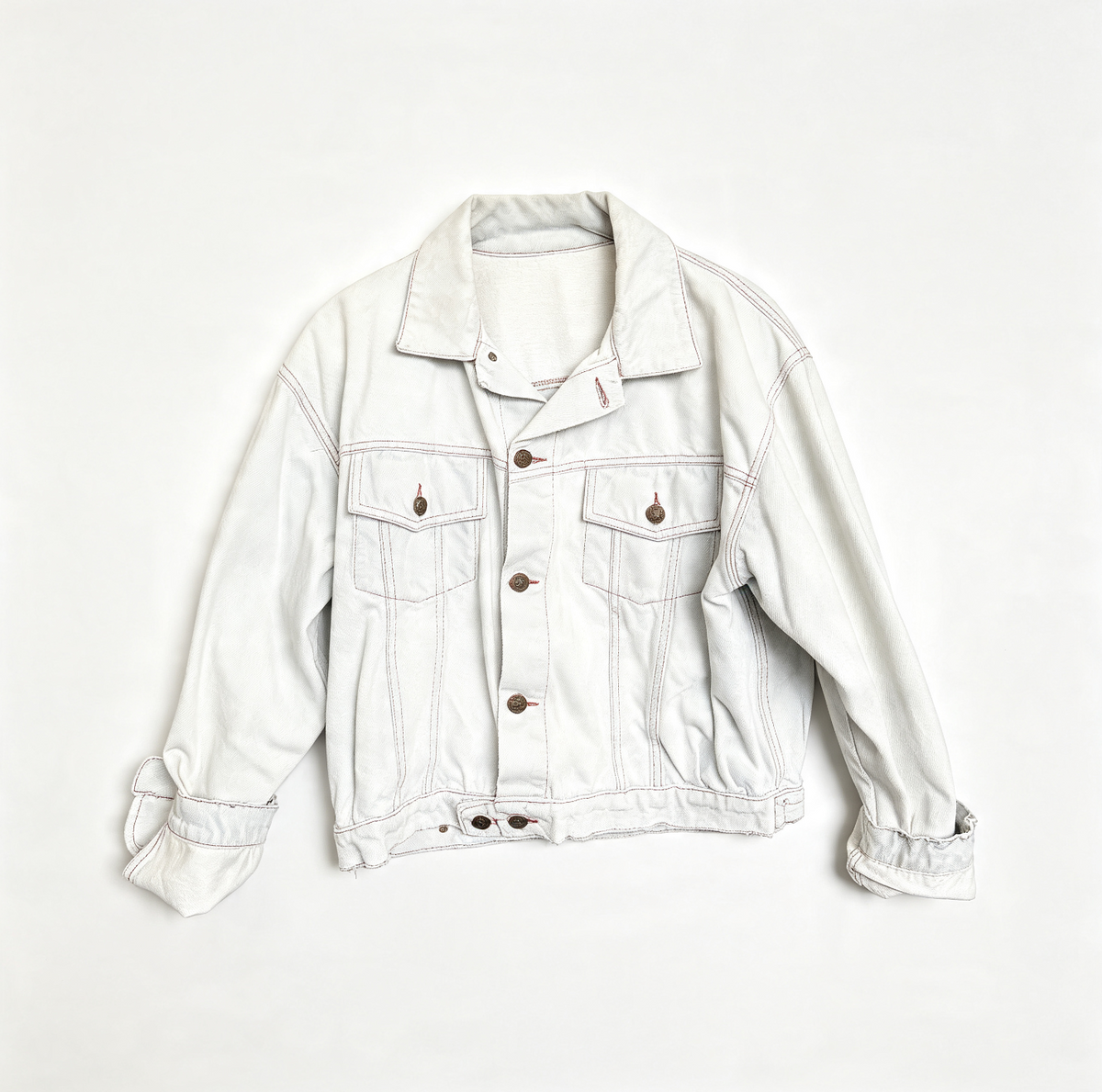 A light-wash off-white denim jacket with brown buttons, laid flat against a clean white background.
