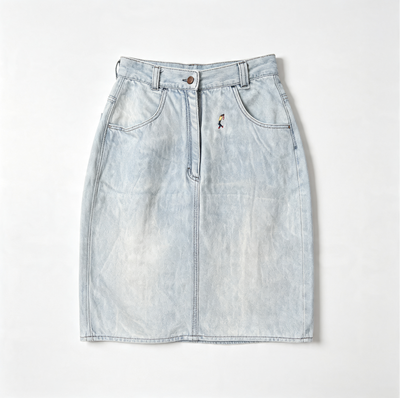 A light-wash blue denim mini skirt with a front button closure, belt loops, and a small embroidered golfer figure detail on the left side, laid flat against a light gray background.