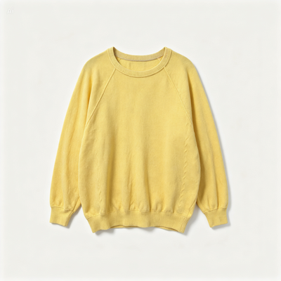A pale yellow crewneck sweatshirt with raglan sleeves, laid flat against a clean off-white background.