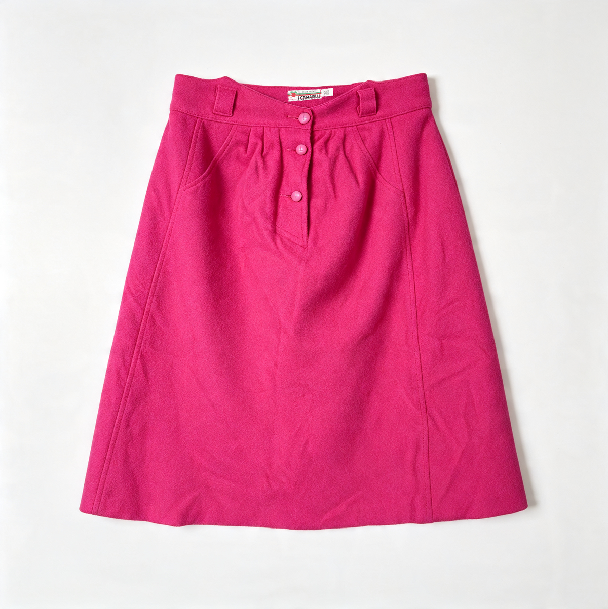 A bright pink A-line wool skirt with a buttoned waistband, laid flat against a light off-white background.